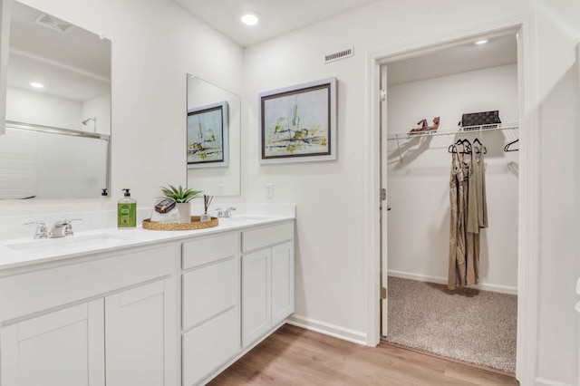 bathroom featuring hardwood / wood-style floors, vanity, and a shower with shower door