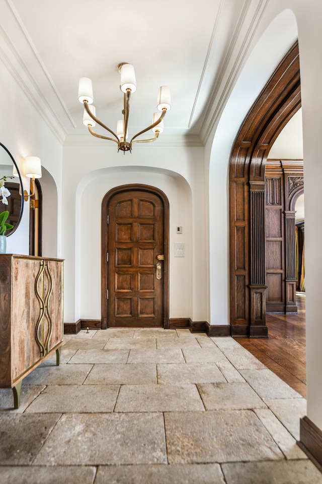 foyer featuring crown molding, wood-type flooring, and an inviting chandelier