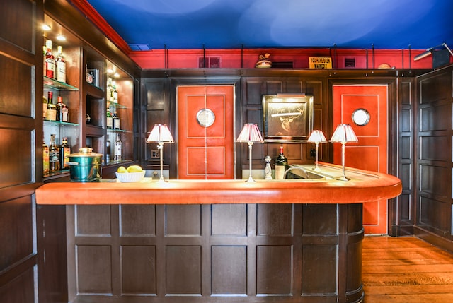 bar with hanging light fixtures, wood-type flooring, and built in features