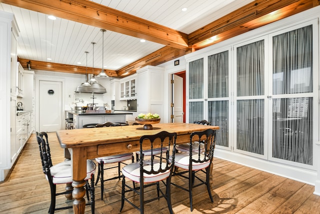 dining space featuring wood ceiling, beamed ceiling, and light wood-type flooring