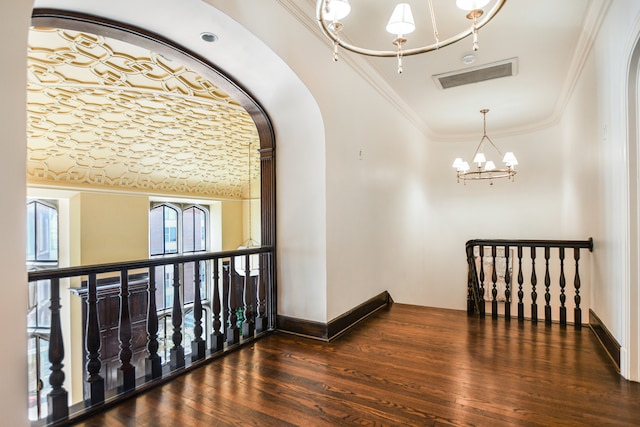 hallway with dark wood-type flooring, crown molding, and a chandelier