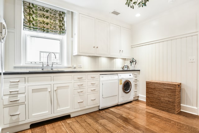 washroom with cabinets, independent washer and dryer, ornamental molding, light hardwood / wood-style floors, and sink