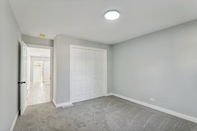 unfurnished bedroom with a closet and light colored carpet