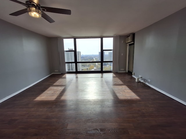 unfurnished room featuring an AC wall unit, dark wood-type flooring, ceiling fan, and expansive windows