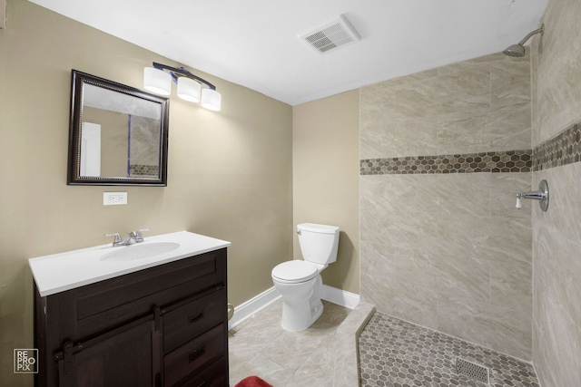 bathroom with toilet, vanity, tile patterned floors, and tiled shower