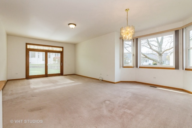 carpeted spare room featuring a chandelier