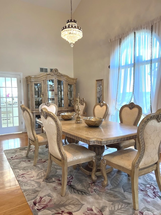 dining space featuring high vaulted ceiling, wood-type flooring, and a chandelier