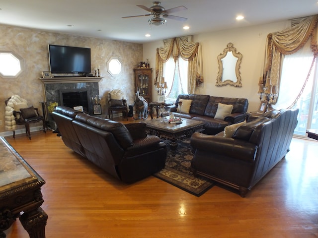 living room with a fireplace, wood-type flooring, and ceiling fan