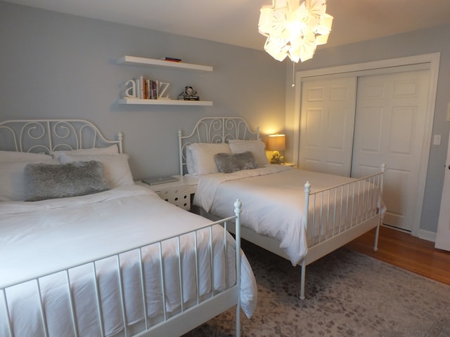 bedroom featuring a notable chandelier, wood-type flooring, and a closet