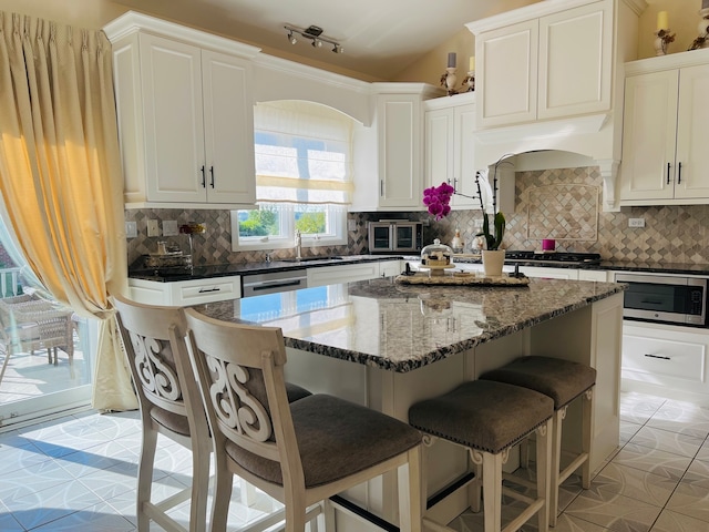 kitchen featuring white cabinetry, decorative backsplash, dark stone counters, and a kitchen island