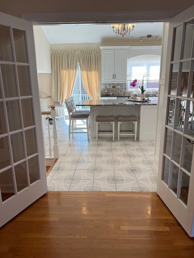 unfurnished dining area with french doors, light hardwood / wood-style floors, a wealth of natural light, and a chandelier