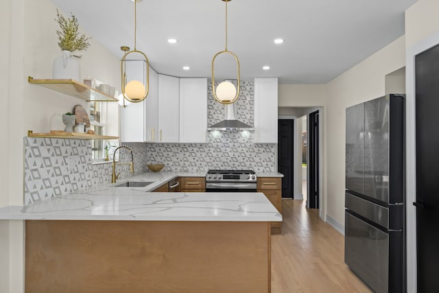 kitchen featuring white cabinetry, sink, kitchen peninsula, stainless steel gas range oven, and light stone countertops