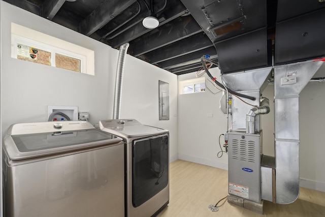 washroom featuring separate washer and dryer, light hardwood / wood-style flooring, electric panel, and heating unit