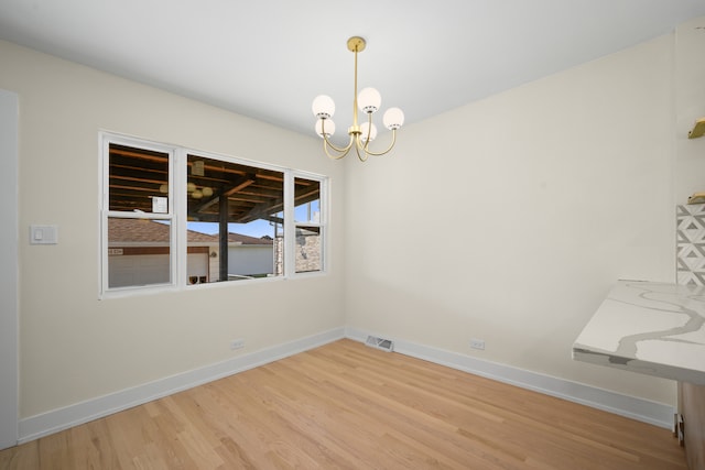 unfurnished dining area featuring an inviting chandelier and hardwood / wood-style flooring