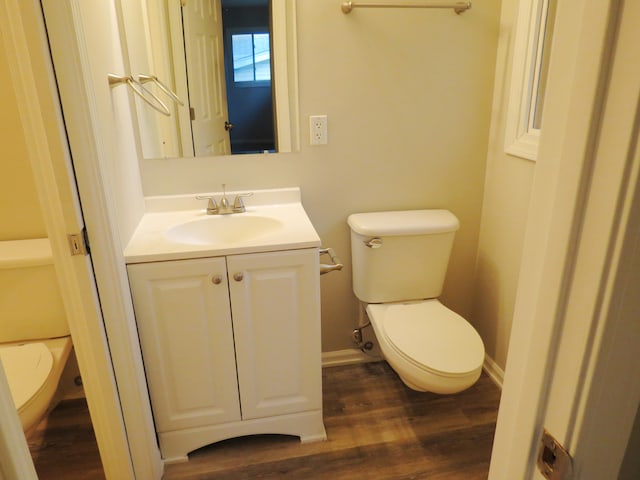 bathroom with toilet, hardwood / wood-style floors, and vanity