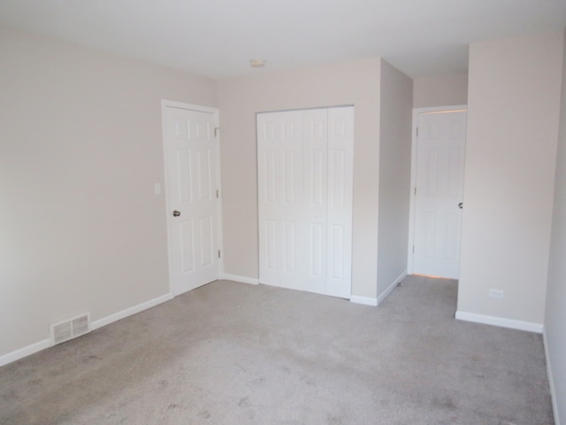 unfurnished bedroom featuring light carpet and a closet