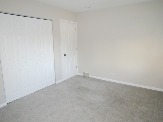 unfurnished bedroom featuring light colored carpet and a closet