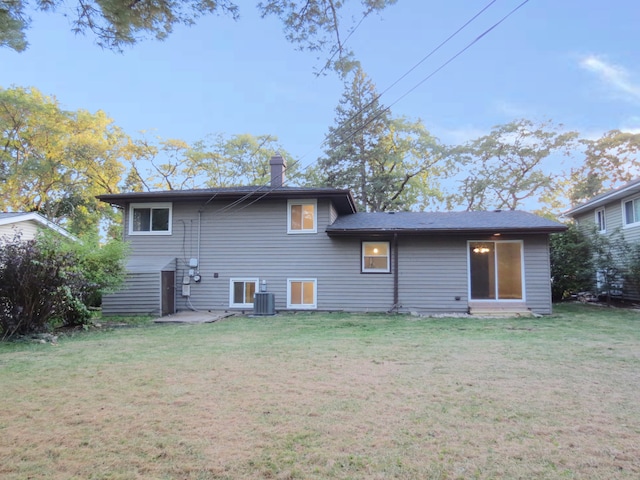 rear view of property with central AC and a lawn