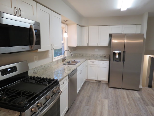 kitchen featuring light hardwood / wood-style flooring, sink, light stone countertops, white cabinets, and appliances with stainless steel finishes