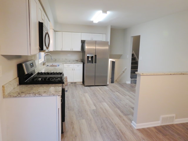 kitchen with appliances with stainless steel finishes, light hardwood / wood-style flooring, white cabinets, and sink