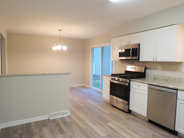 kitchen featuring white cabinetry, stainless steel appliances, decorative light fixtures, and light wood-type flooring