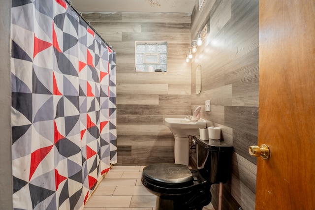 bathroom with wood walls, a shower with shower curtain, and toilet