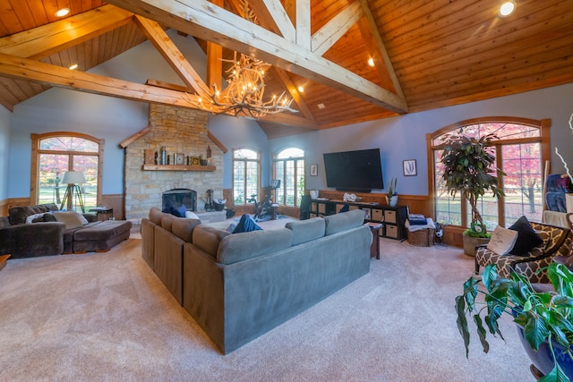 carpeted living room featuring beamed ceiling, a fireplace, high vaulted ceiling, and wooden ceiling