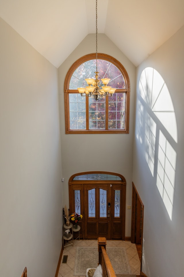 tiled entrance foyer featuring lofted ceiling and a chandelier