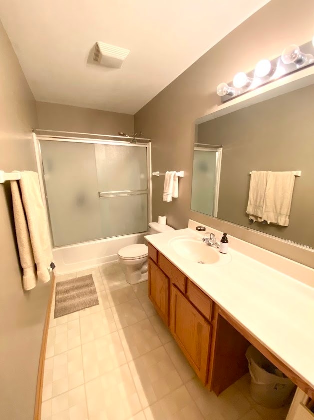 full bathroom with vanity, toilet, tile patterned floors, and bath / shower combo with glass door