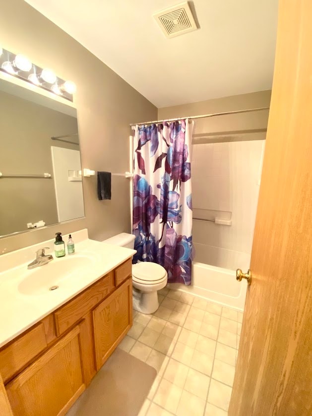 full bathroom featuring vanity, shower / bath combo with shower curtain, toilet, and tile patterned flooring