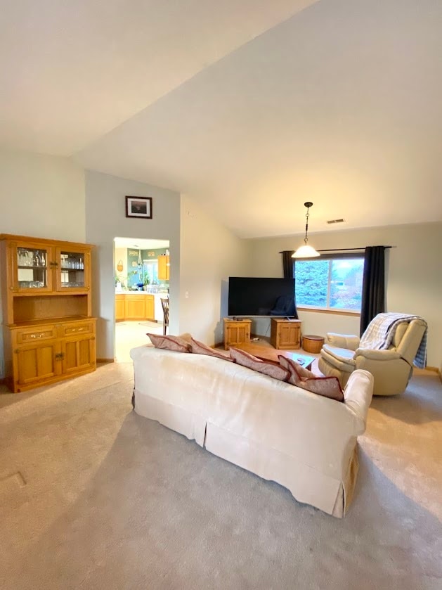 carpeted living room featuring vaulted ceiling