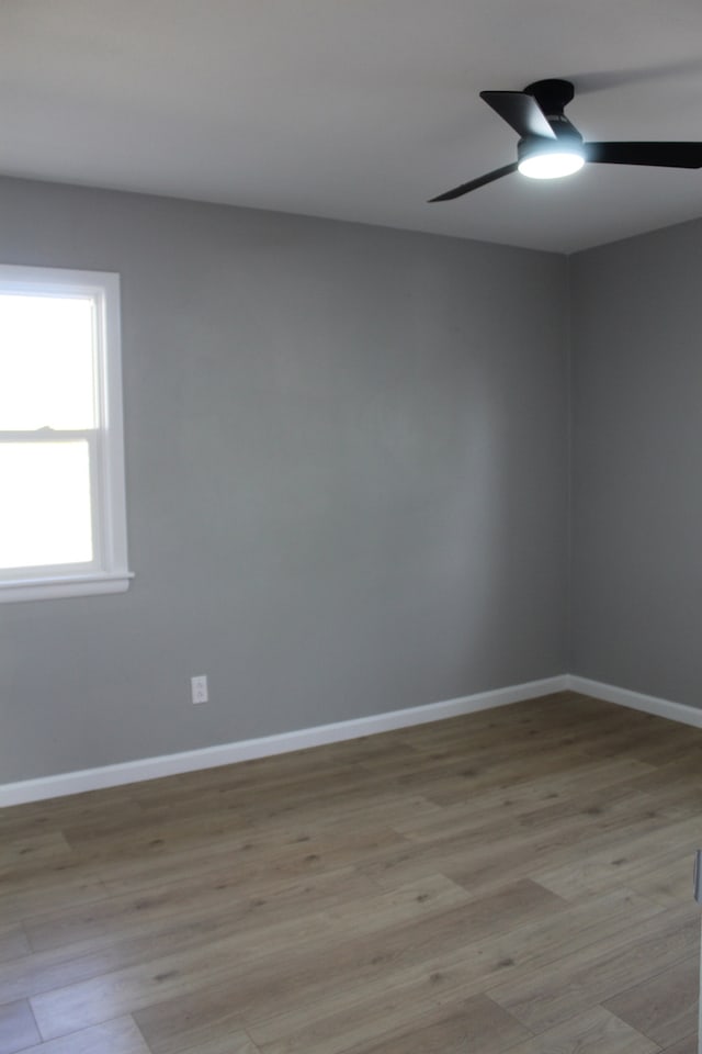 spare room with light wood-style floors, ceiling fan, and baseboards