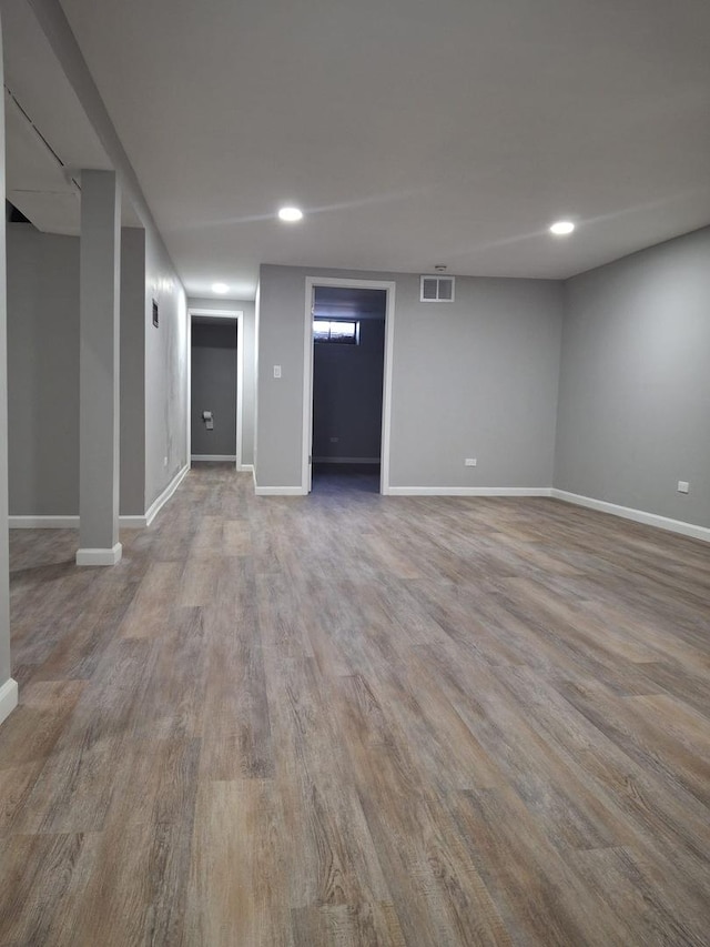 finished below grade area with baseboards, recessed lighting, visible vents, and light wood-style floors