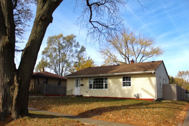 rear view of property with a yard, a chimney, and fence