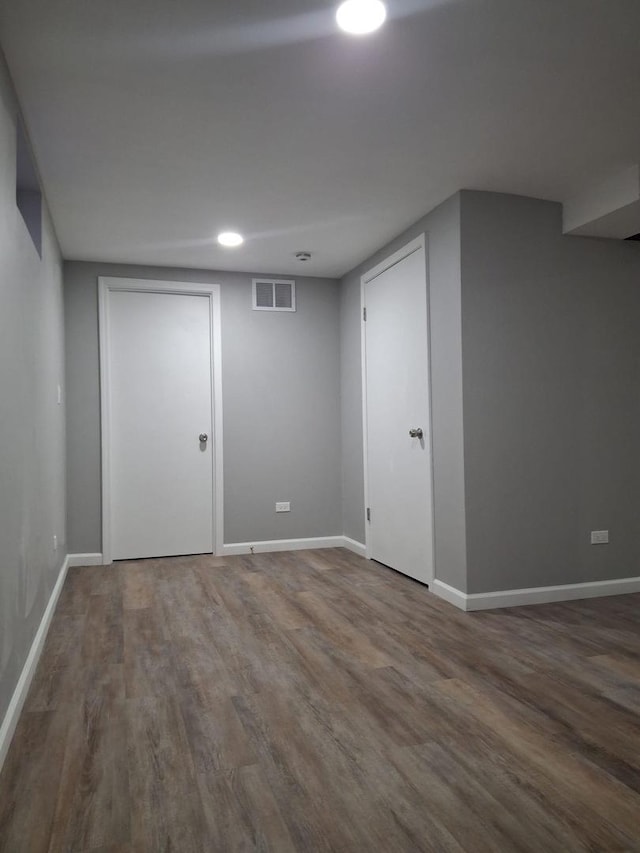 finished below grade area featuring baseboards, visible vents, and wood finished floors