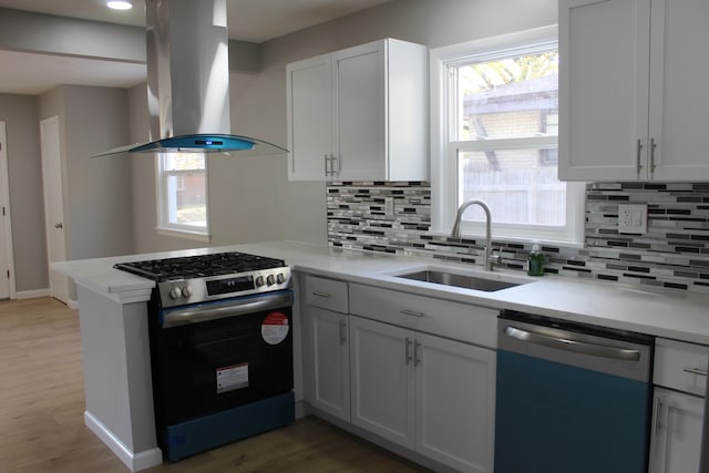 kitchen featuring appliances with stainless steel finishes, light countertops, white cabinetry, and island range hood