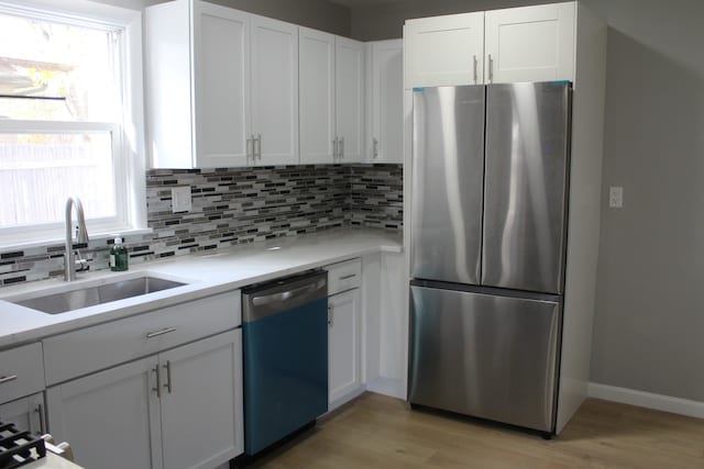 kitchen with white cabinetry, stainless steel appliances, a sink, and light countertops