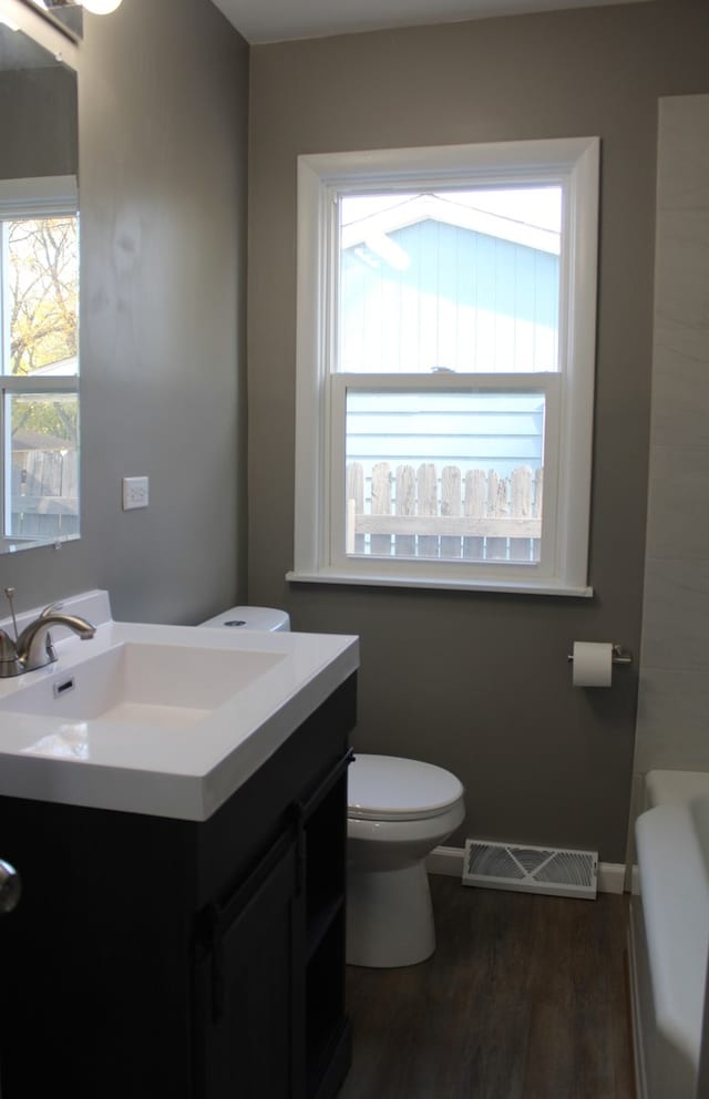 full bathroom with toilet, wood finished floors, vanity, visible vents, and baseboards