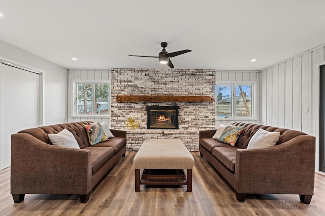 living room with hardwood / wood-style flooring, ceiling fan, wood walls, and a healthy amount of sunlight