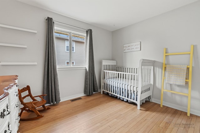 bedroom featuring wood-type flooring and a crib