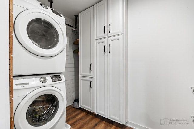 washroom featuring cabinets, stacked washer and dryer, and dark wood-type flooring