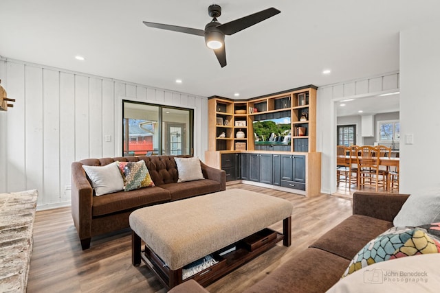 living room featuring hardwood / wood-style floors, ceiling fan, and wood walls