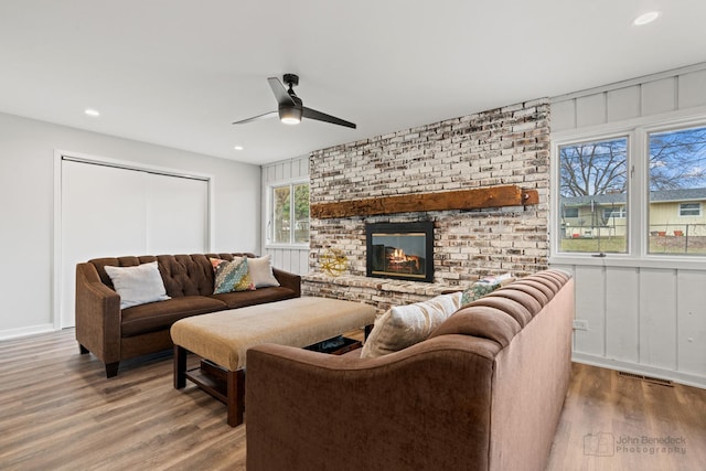 living room with ceiling fan, hardwood / wood-style floors, and a brick fireplace