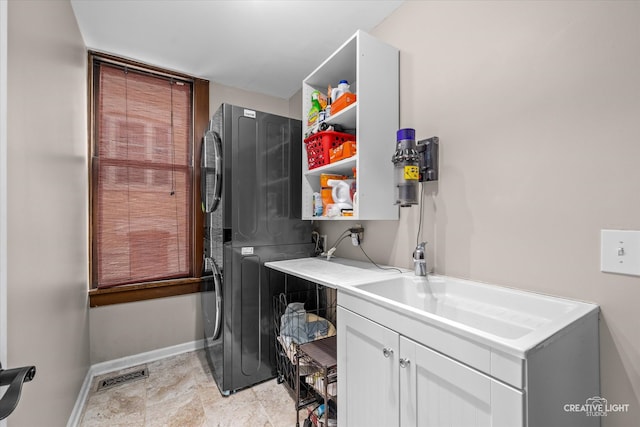 laundry area featuring stacked washer and dryer, cabinets, and sink