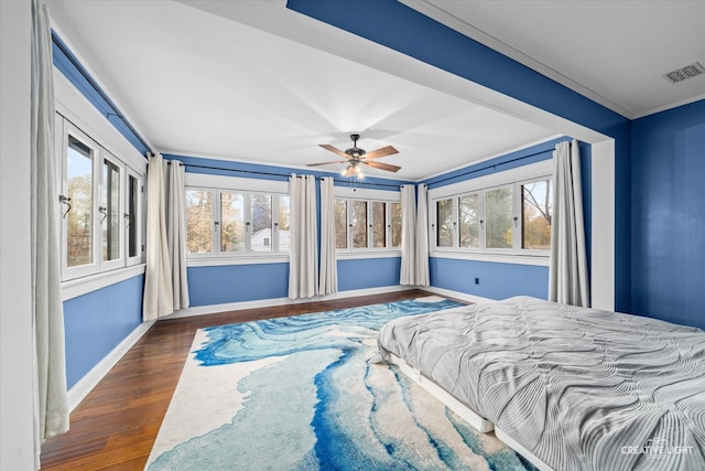 bedroom featuring dark hardwood / wood-style flooring, ornamental molding, and ceiling fan