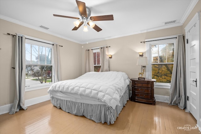 bedroom featuring ornamental molding, light hardwood / wood-style floors, multiple windows, and ceiling fan