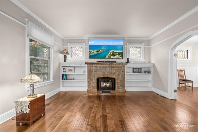 living room with wood-type flooring, a tile fireplace, and ornamental molding