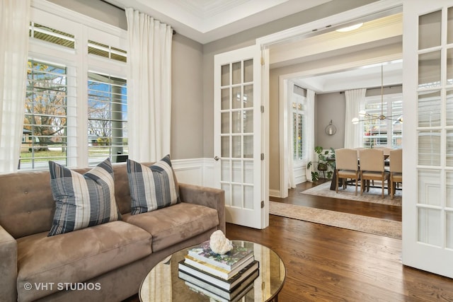 living room featuring crown molding, plenty of natural light, a notable chandelier, and dark hardwood / wood-style flooring