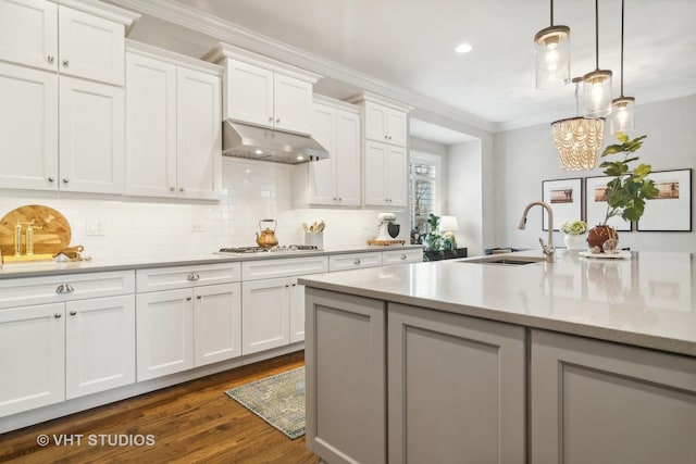 kitchen featuring hanging light fixtures, crown molding, sink, and white cabinets