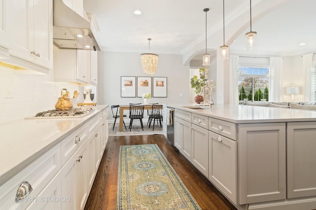 kitchen featuring pendant lighting, range hood, white cabinetry, a kitchen island with sink, and gas stovetop